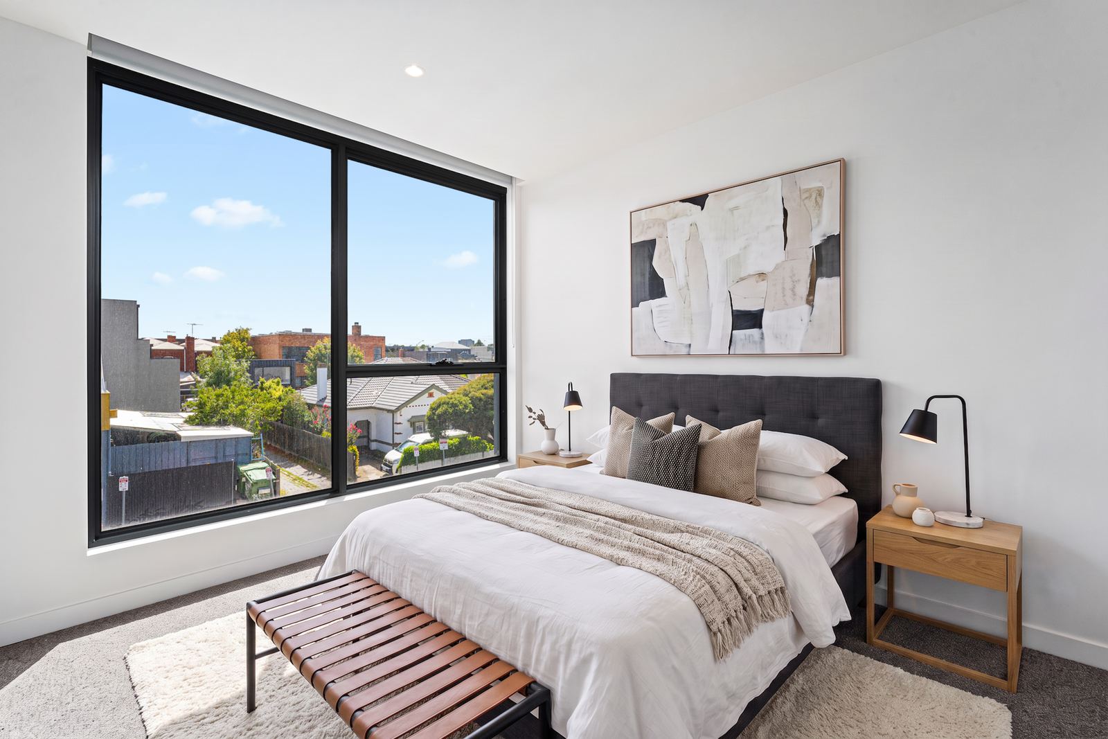 Modern virtual staging of a master bedroom with a charcoal upholstered bed and timber bench