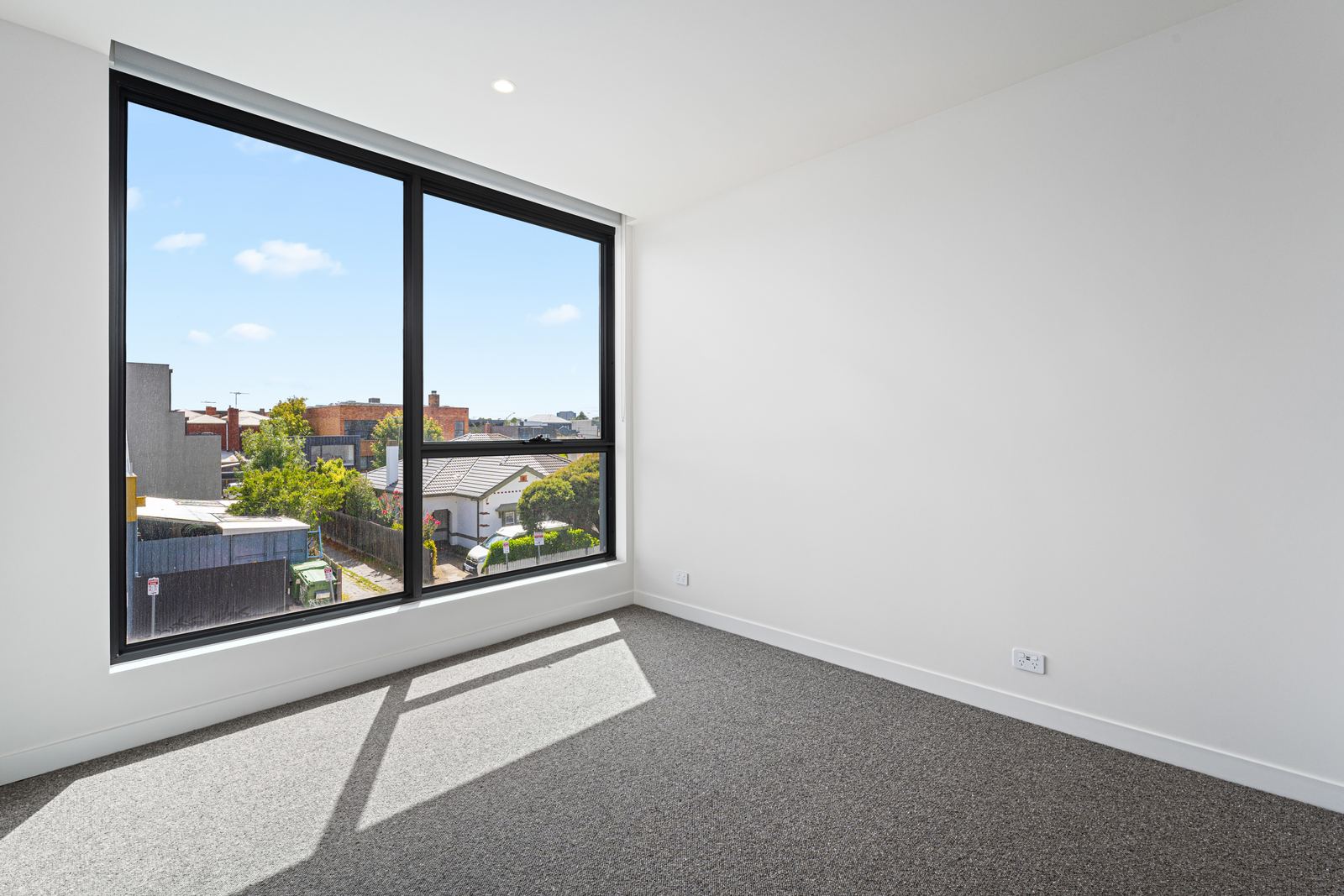 Virtual Staging Before and After 10 Empty bedroom with a large city-facing window before virtual staging