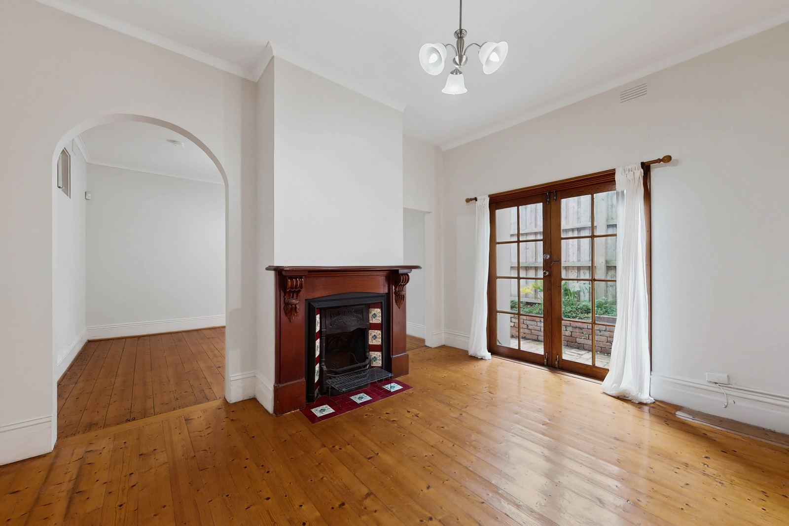 Virtual Staging Before and After 8 Empty period living room with a timber fireplace and archway before virtual staging