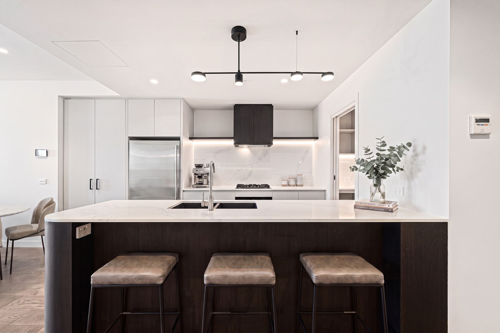 Virtual Staging Services 2 Empty kitchen with a dark timber island and white cabinetry before virtual staging